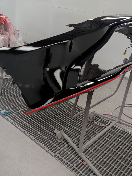 Body panel with glossy black paint and red accent