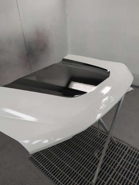 Hood scoop panel being painted — white with black accent
